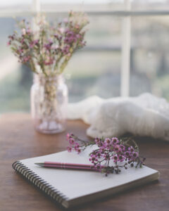 Image of journal on wood table with pen and tiny pink flowers