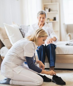 Nurse aid caregiver helping an older woman on with her shoes